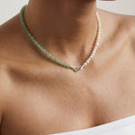 Beaded necklace featuring green and silver beads on a person with a neutral background