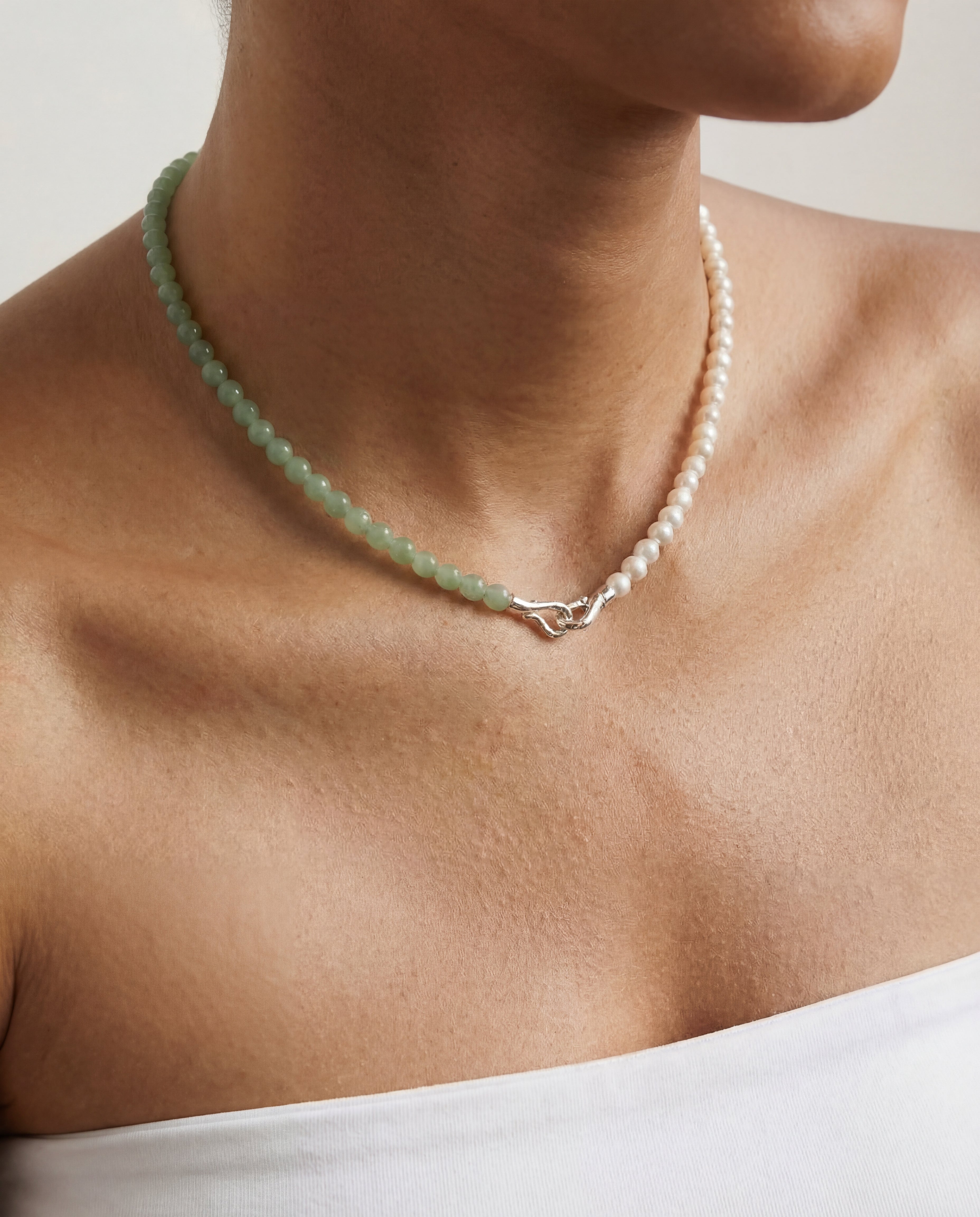 Beaded necklace featuring green and silver beads on a person with a neutral background