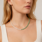 Woman wearing a green beaded necklace with mixed green and silver beads, against a neutral background