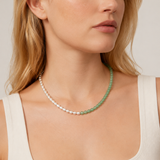Woman wearing a green beaded necklace with mixed green and silver beads, against a neutral background