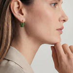 Close-up of a woman wearing green beaded hoop earrings with a neutral background