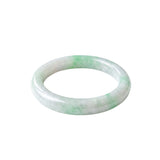 A slightly angled top-down shot of a light green and white jade bangle bracelet with a smooth, polished finish, shown on a plain white background.