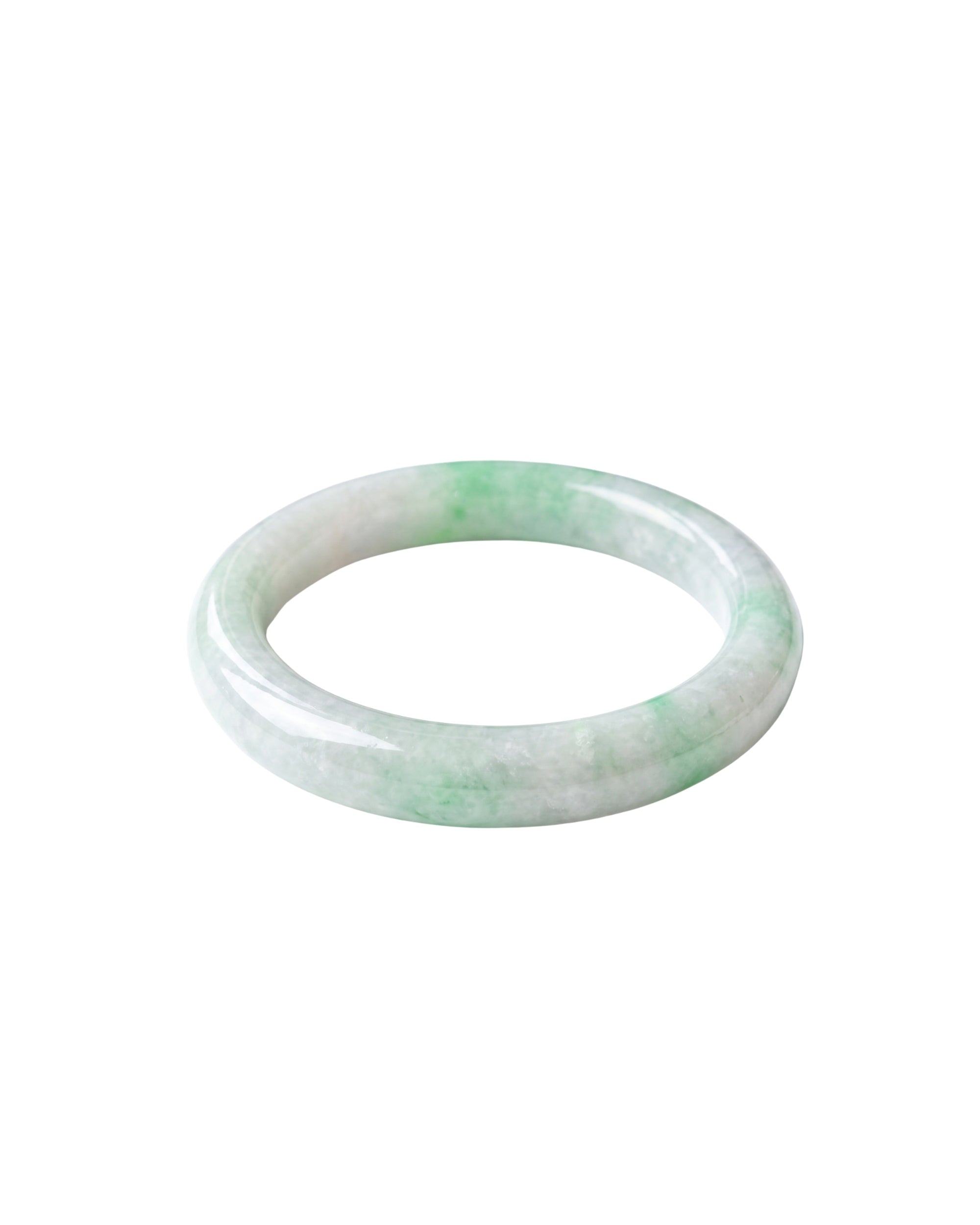 A slightly angled top-down shot of a light green and white jade bangle bracelet with a smooth, polished finish, shown on a plain white background.