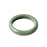 A smooth, polished jadeite bangle bracelet in a light green color, shown against a plain white background.