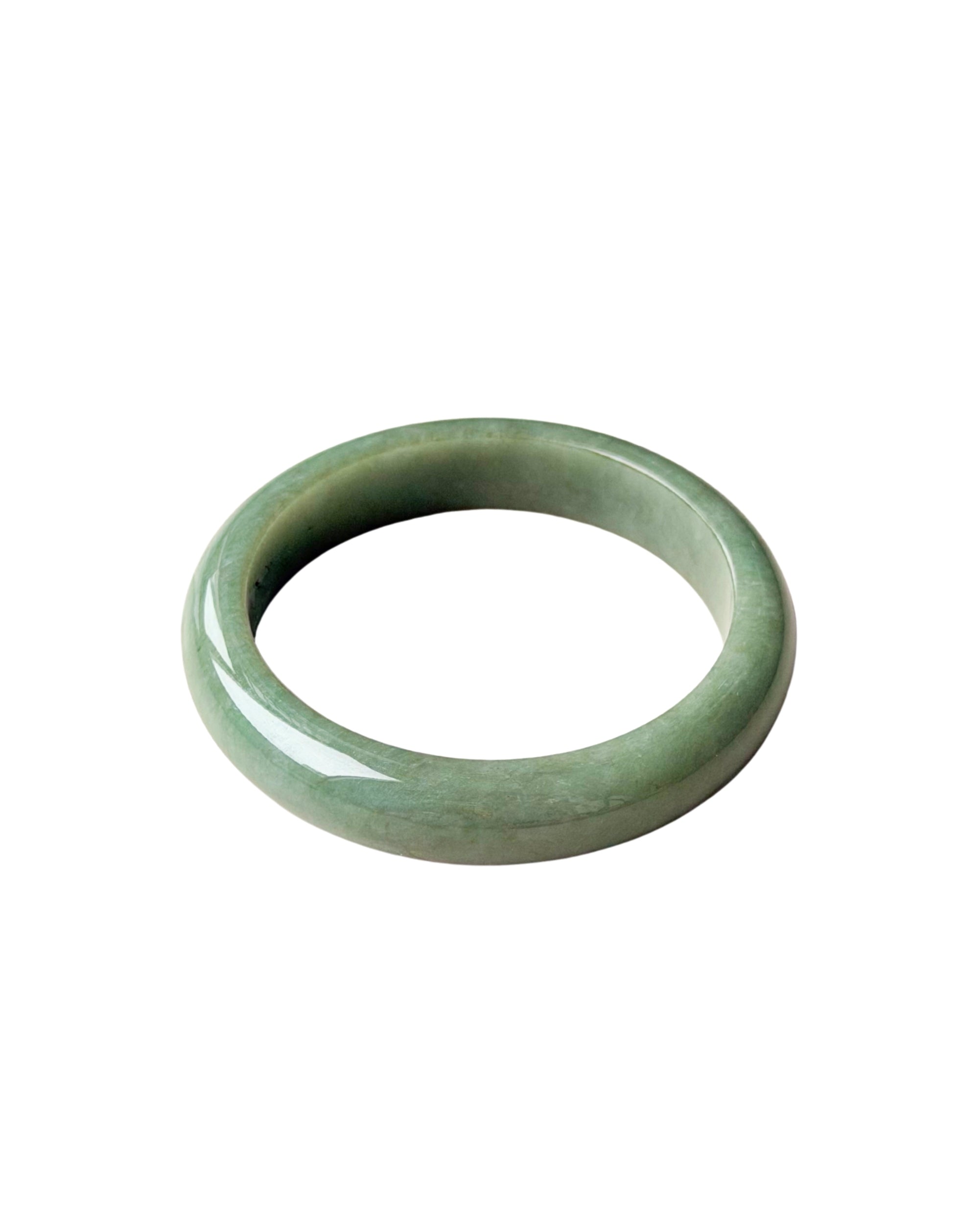 A smooth, polished jadeite bangle bracelet in a light green color, shown against a plain white background.