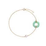 A delicate gold chain bracelet featuring a light green jadeite ring pendant and a single white pearl bead, displayed on a clean white background.