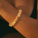 Gold bracelet on a wrist with a warm glow