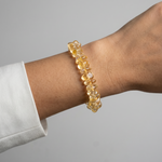 Yellow beaded bracelet on a wrist with a gray background