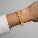 Yellow beaded bracelet on a wrist with a gray background