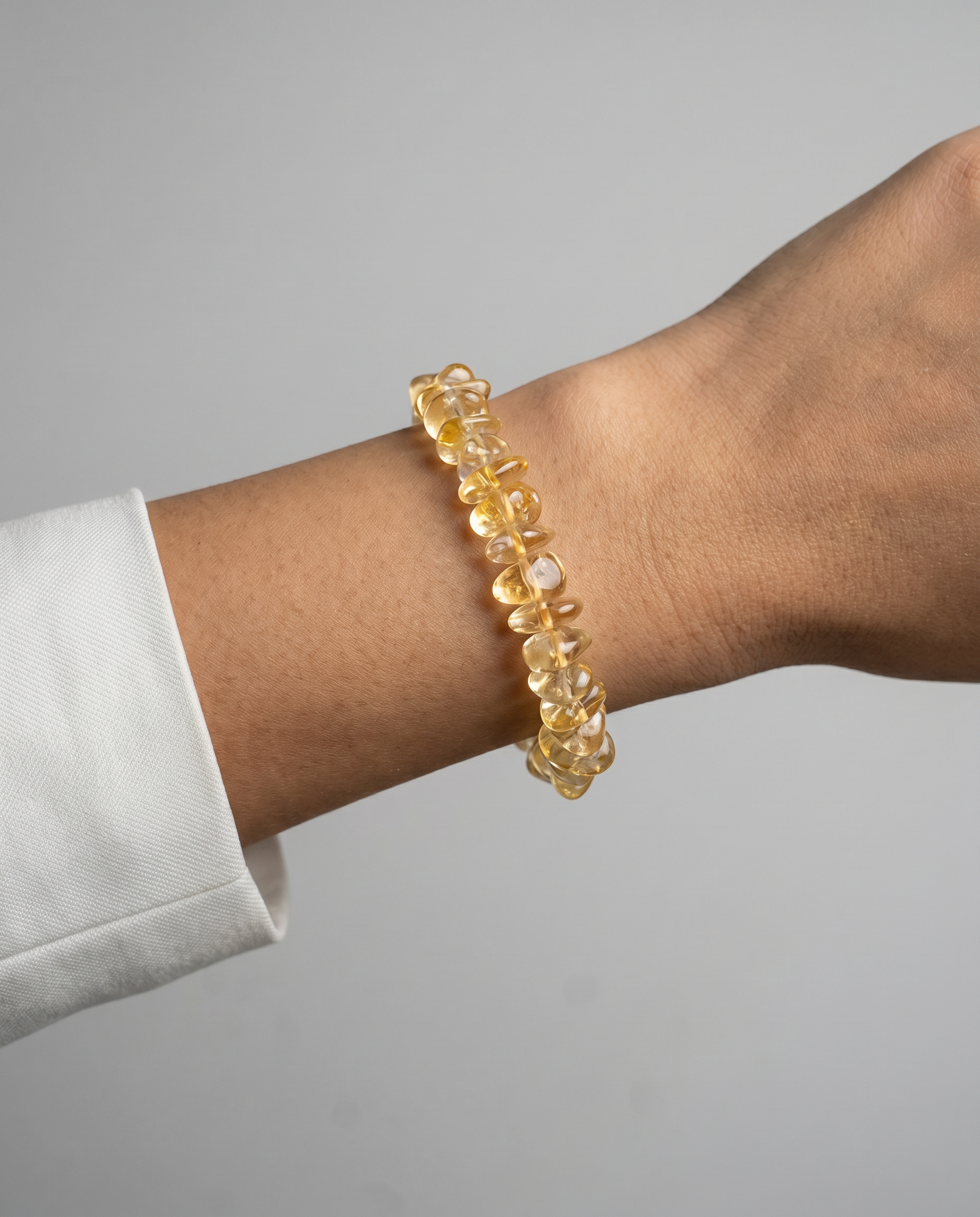 Yellow beaded bracelet on a wrist with a gray background