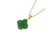 Green clover-shaped pendant on a gold chain against a white background, top view