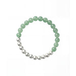 Flatlay shot of a green and silver beaded bracelet showcasing a half-and-half arrangement of polished round beads.