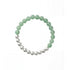 Flatlay shot of a green and silver beaded bracelet showcasing a half-and-half arrangement of polished round beads.