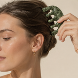 Person using a green hair comb on their hair against a neutral background