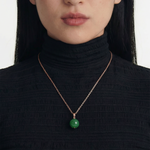 Person wearing a black turtleneck with a green spherical jade pendant necklace, close up