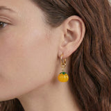 Close-up of a person wearing a pumpkin-shaped earring with a gold hoop.
