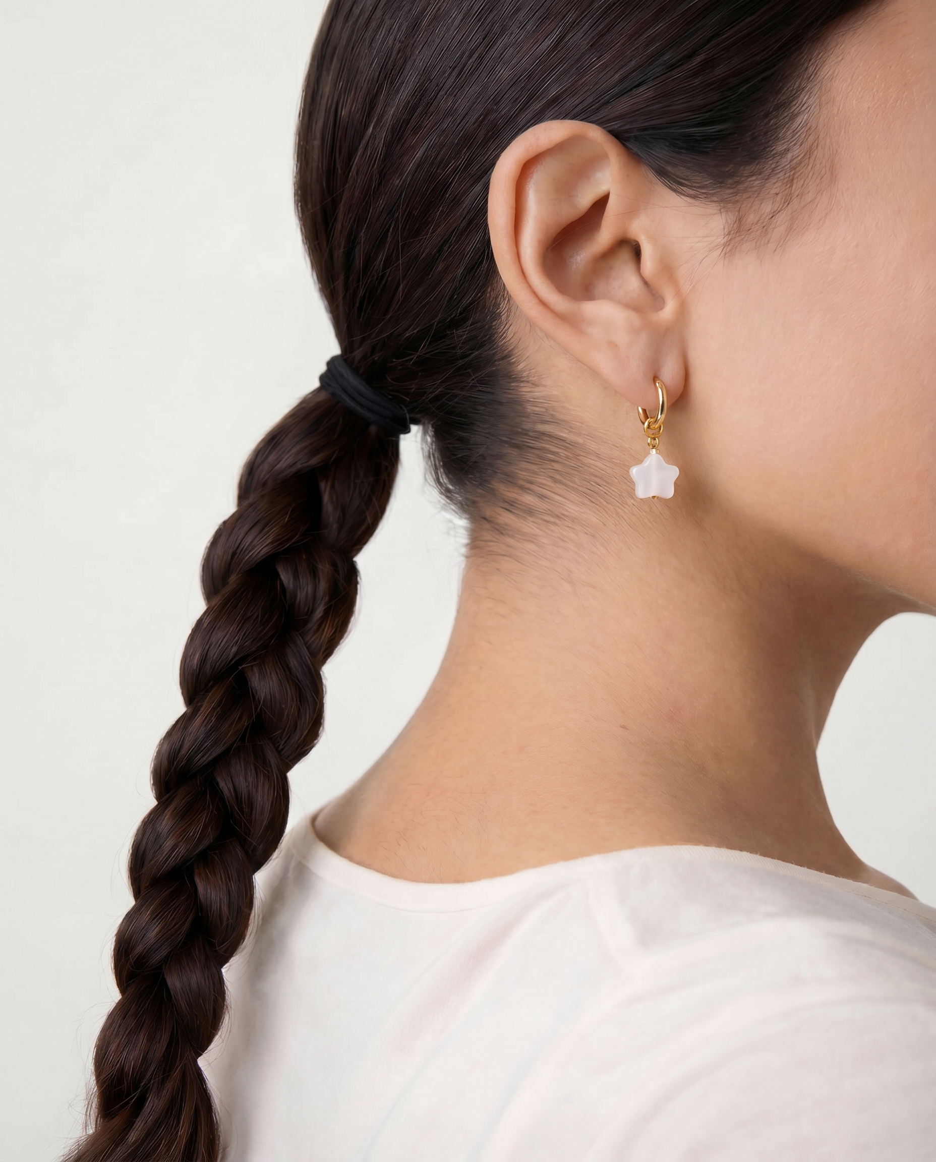 Close-up of a person wearing a star-shaped earring with a plain background