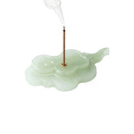 Incense holder shaped like a cloud with a smoking incense stick on a white background