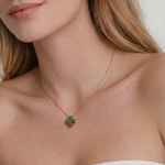 Close-up of a woman wearing a gold necklace with a green clover-shaped jade pendant.