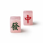 Two pink crystal mahjong tiles, one showing a green Chinese character and the other showing a red Chinese character, photographed on a clean white background.