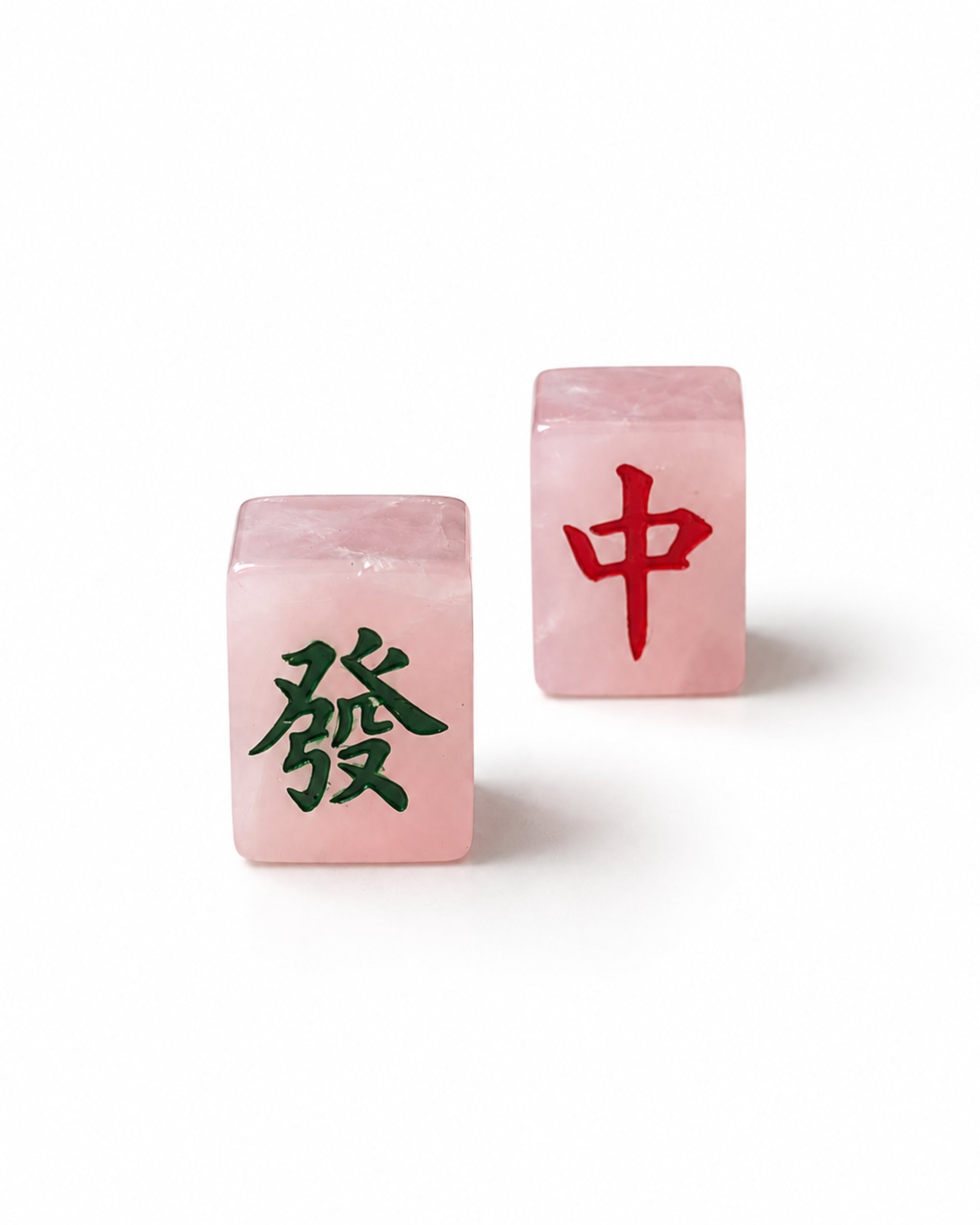 Two pink crystal mahjong tiles, one showing a green Chinese character and the other showing a red Chinese character, photographed on a clean white background.