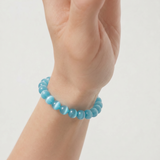 Turquoise beaded bracelet on a wrist against a light gray background