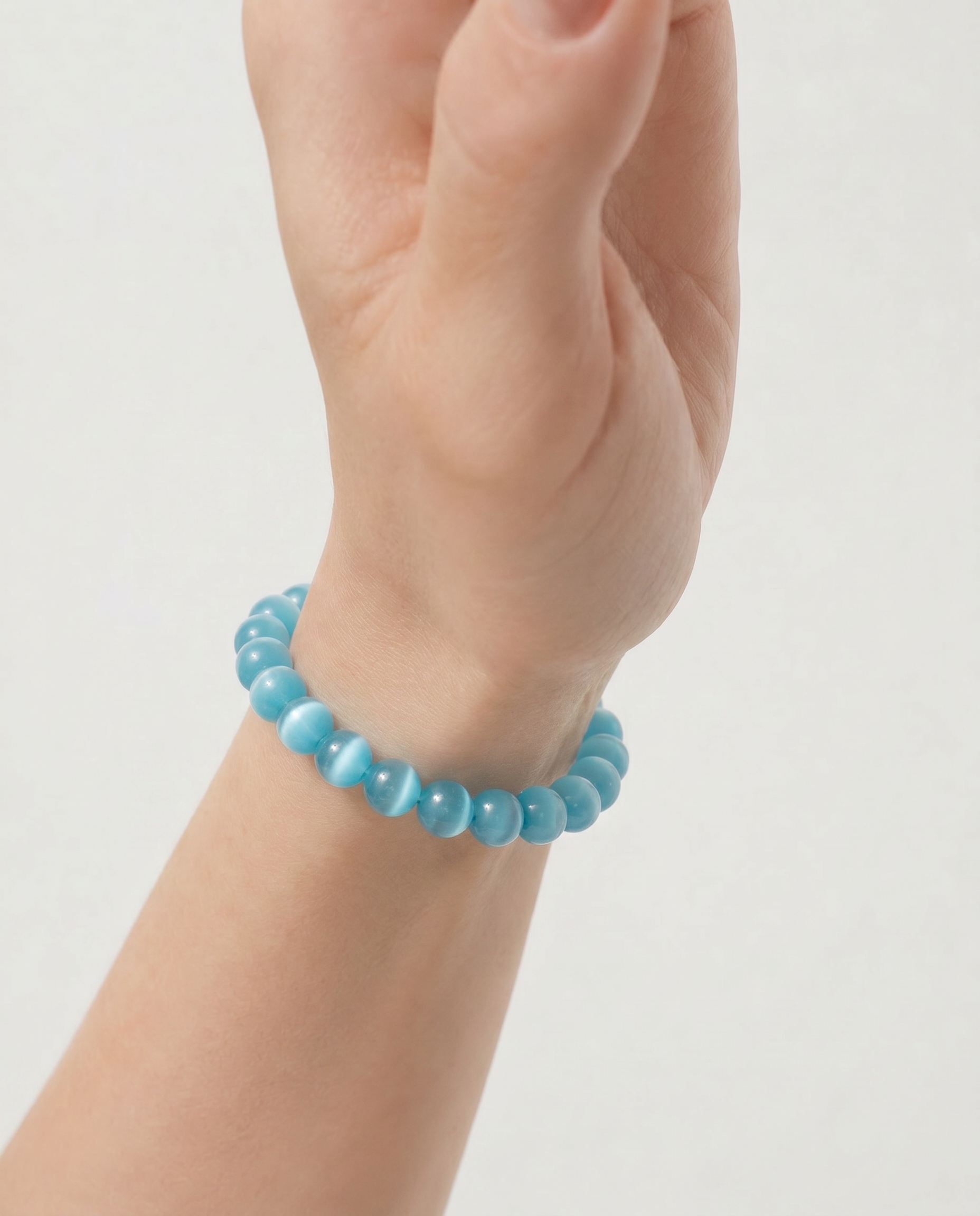 Turquoise beaded bracelet on a wrist against a light gray background