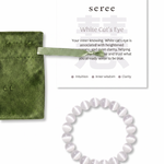 White cat's eye beaded bracelet with green jewelry bag and information card on a white background