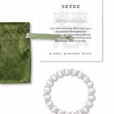 White cat's eye beaded bracelet with green jewelry bag and information card on a white background