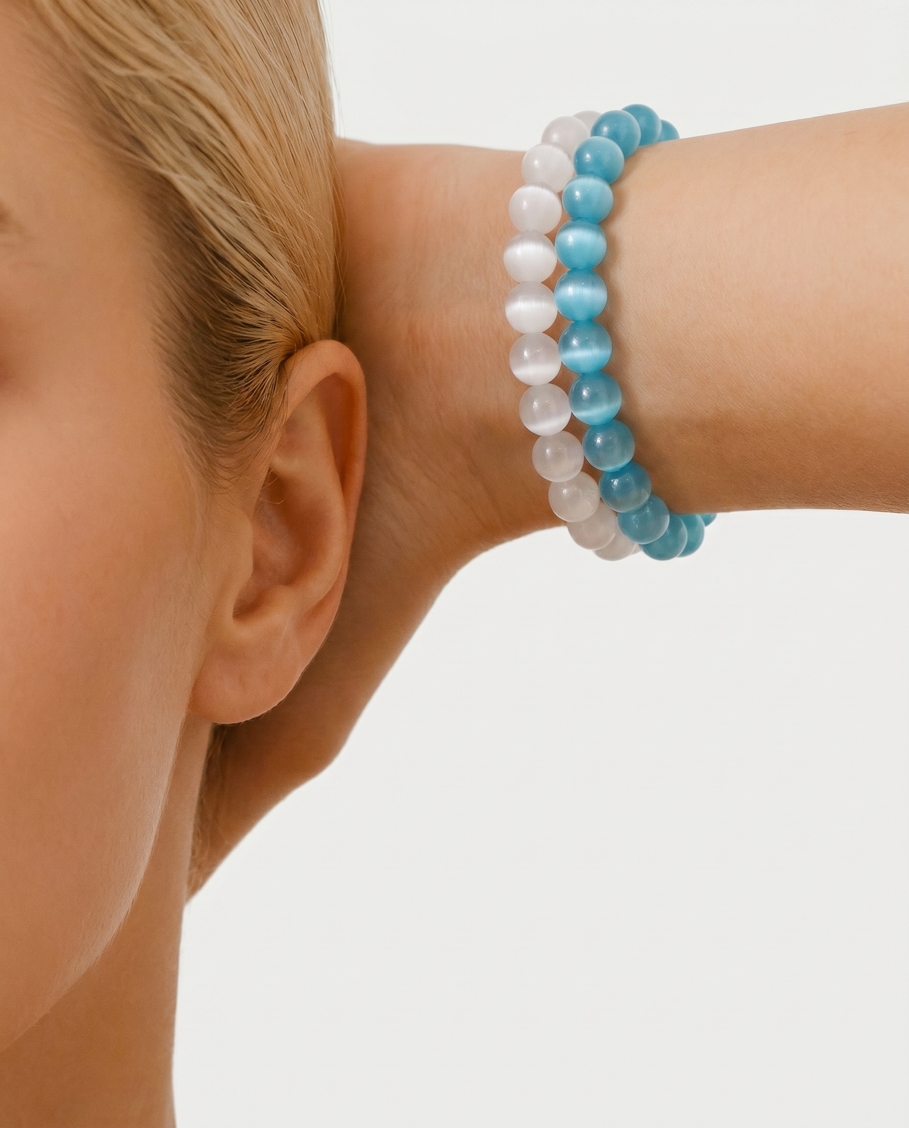Close-up of a person wearing a blue and white beaded bracelet on a plain background