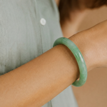 Person wearing a green bracelet on a blurred background