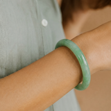 Person wearing a green bracelet on a blurred background