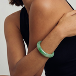 Person wearing a green bracelet on a plain background