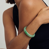 Person wearing a green bracelet on a plain background