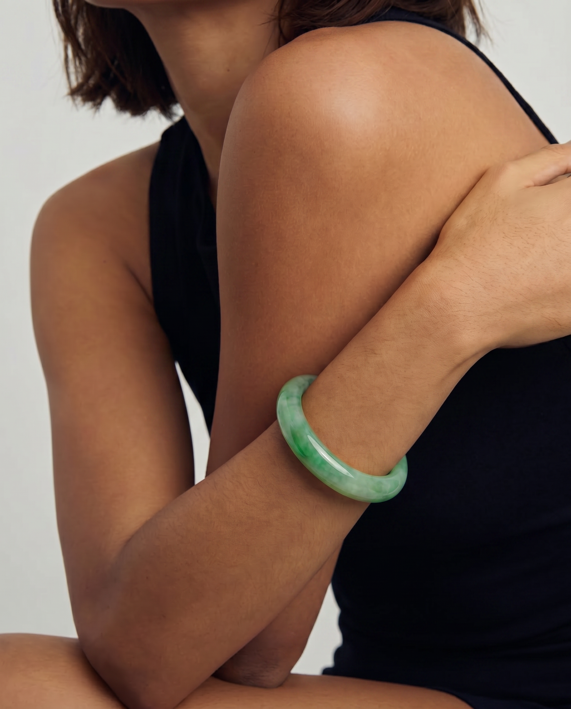 Person wearing a green bracelet on a plain background