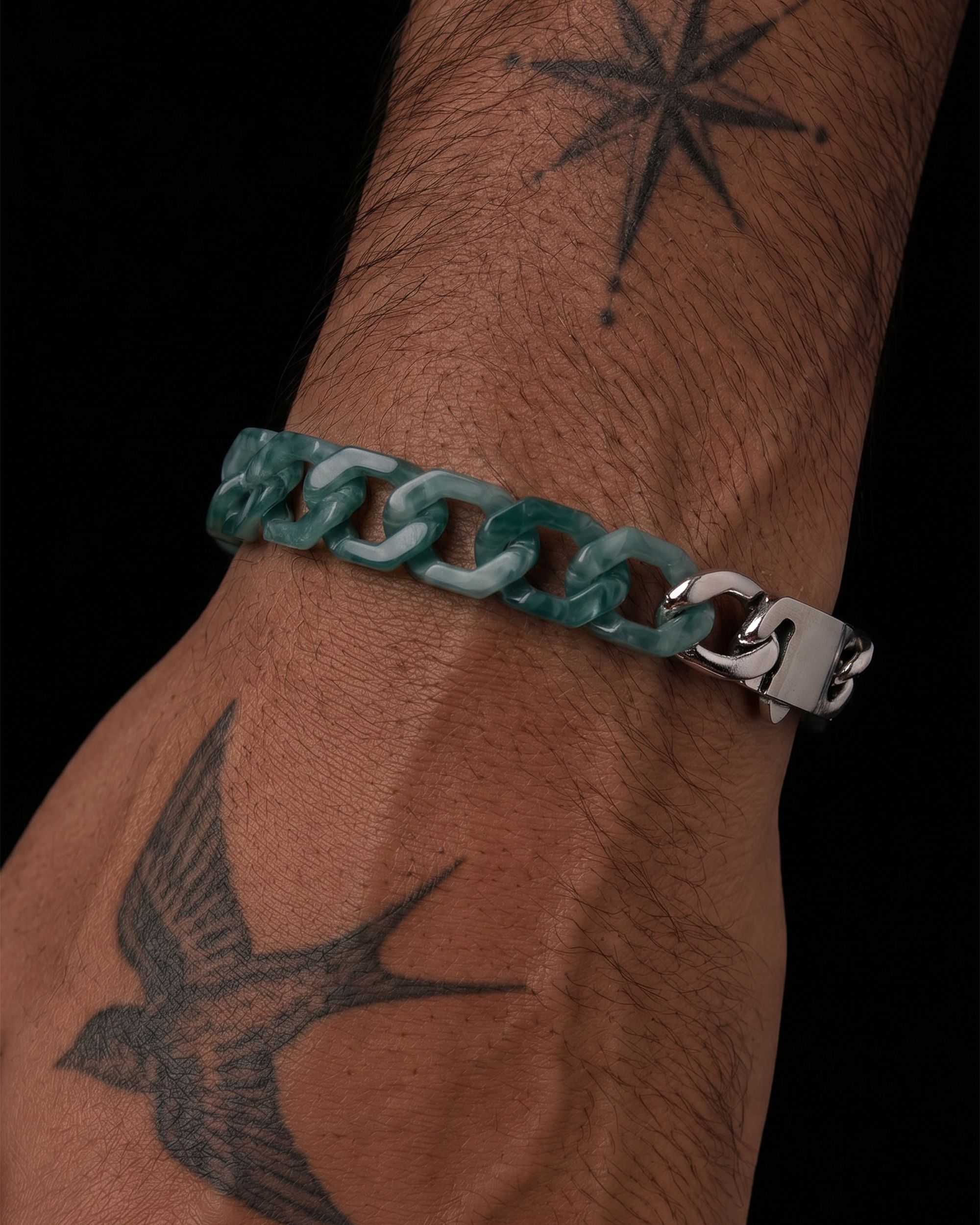 Teal chain bracelet on a wrist with tattoos