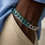 Close-up of a person's arm wearing a teal chain bracelet with a blue sleeve.