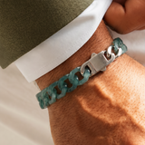 Person wearing a green chain bracelet on a neutral background