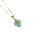 Close-up shot of a necklace with a green heart-shaped pendant on a gold-plated chain against a white background