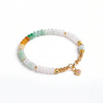 Beaded bracelet with gold accents and a heart charm on a white background