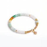 Beaded bracelet with gold accents and a heart charm on a white background