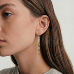 Close-up of a woman wearing beaded earrings with a neutral background