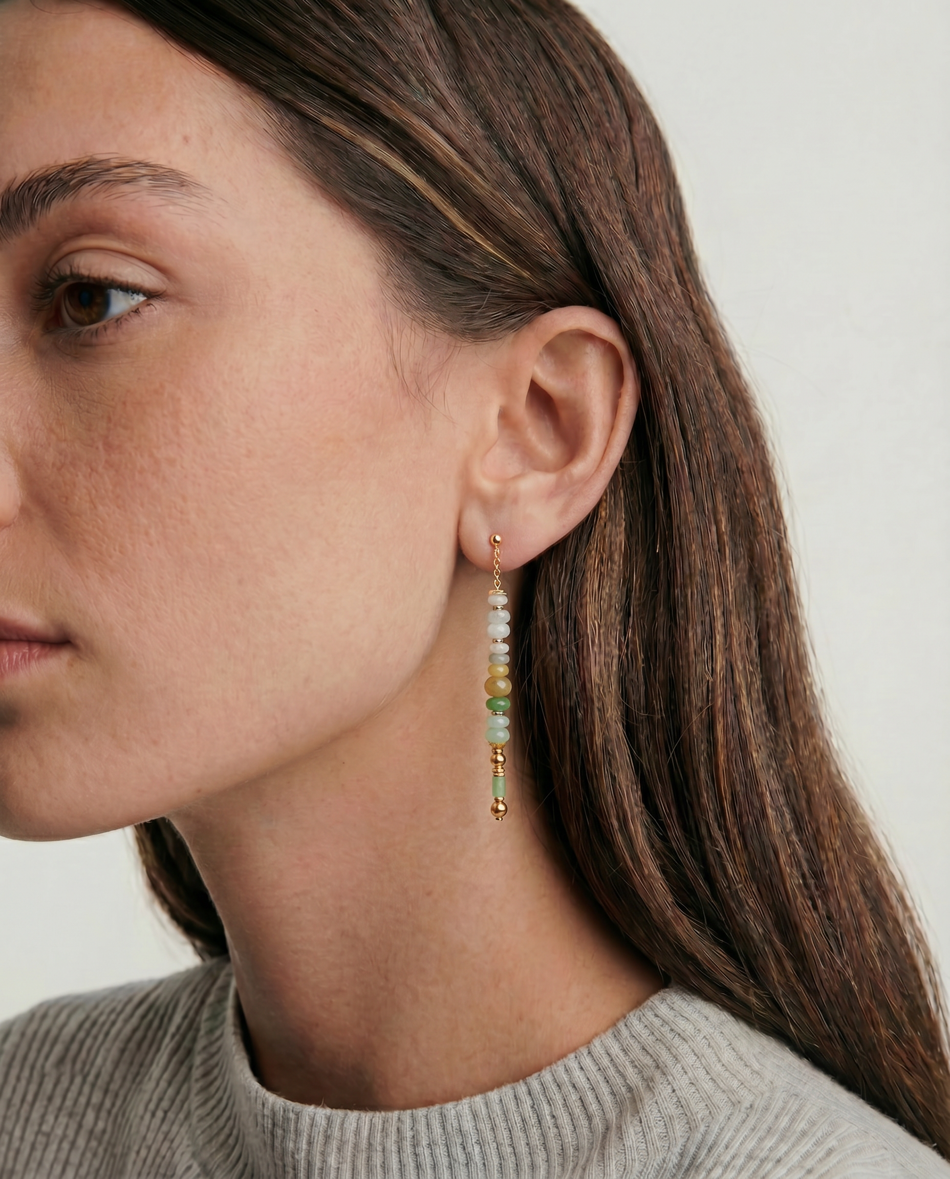 Close-up of a woman wearing beaded earrings with a neutral background