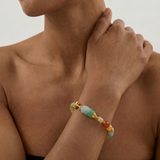 Close-up of a person wearing a colorful beaded jade bracelet on a neutral background