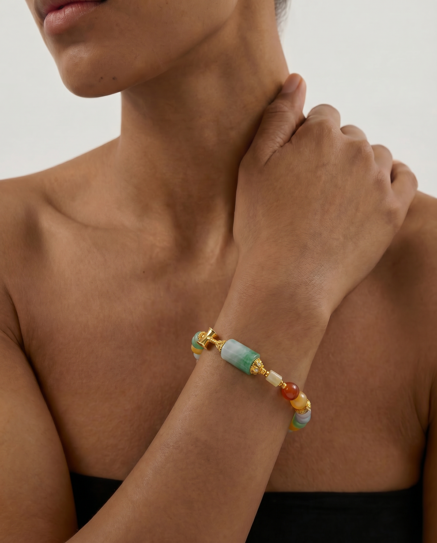Close-up of a person wearing a colorful beaded jade bracelet on a neutral background