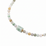 Necklace with multicolored jade beads and a jade barrel pendant on a white background, close-up