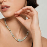 Woman wearing a multicolored jade beaded necklace with a neutral background