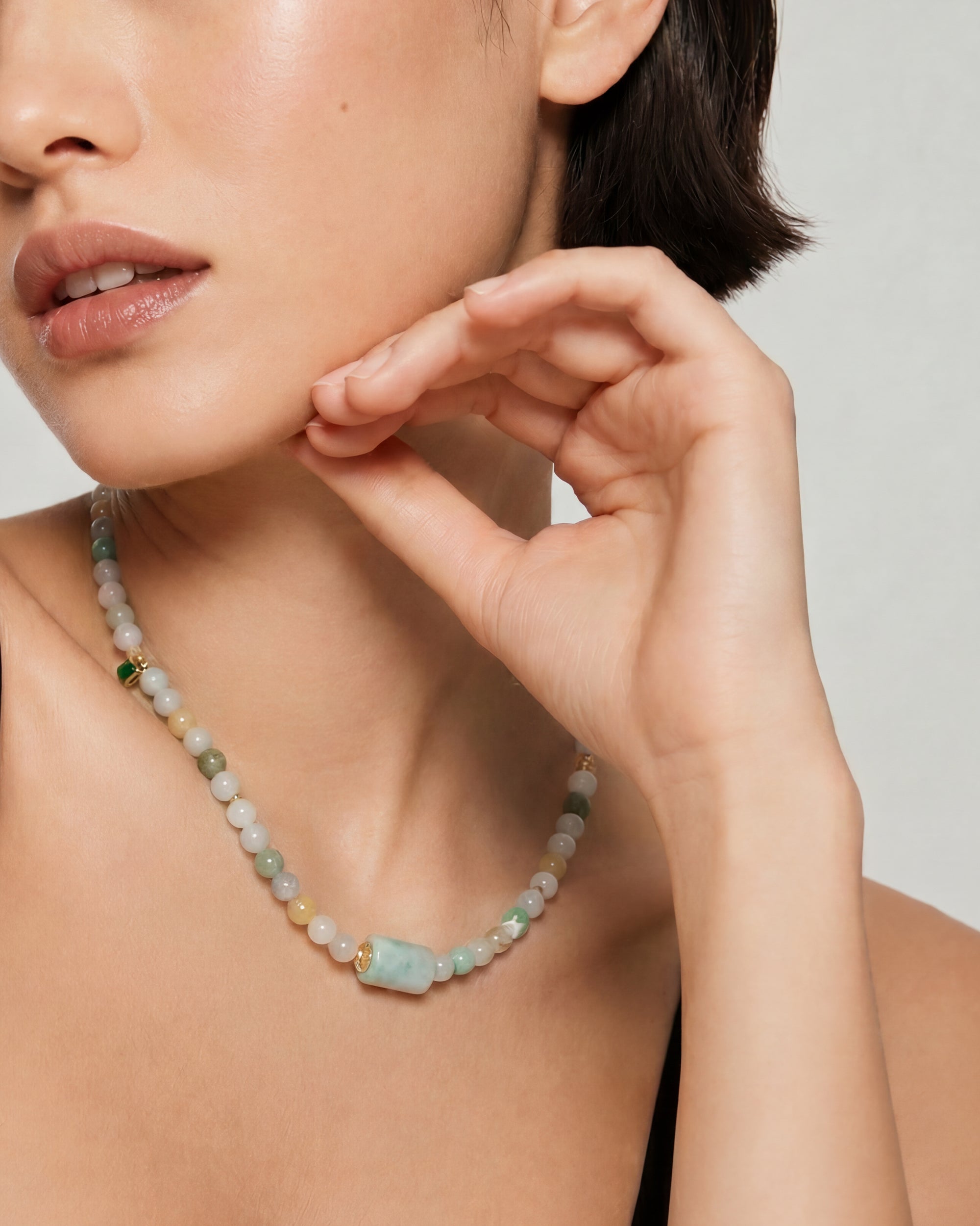 Woman wearing a multicolored jade beaded necklace with a neutral background