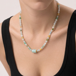 Necklace with multicolored jade beads worn by a person in a black top on a light background