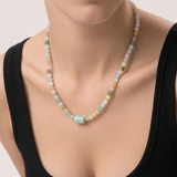 Necklace with multicolored jade beads worn by a person in a black top on a light background